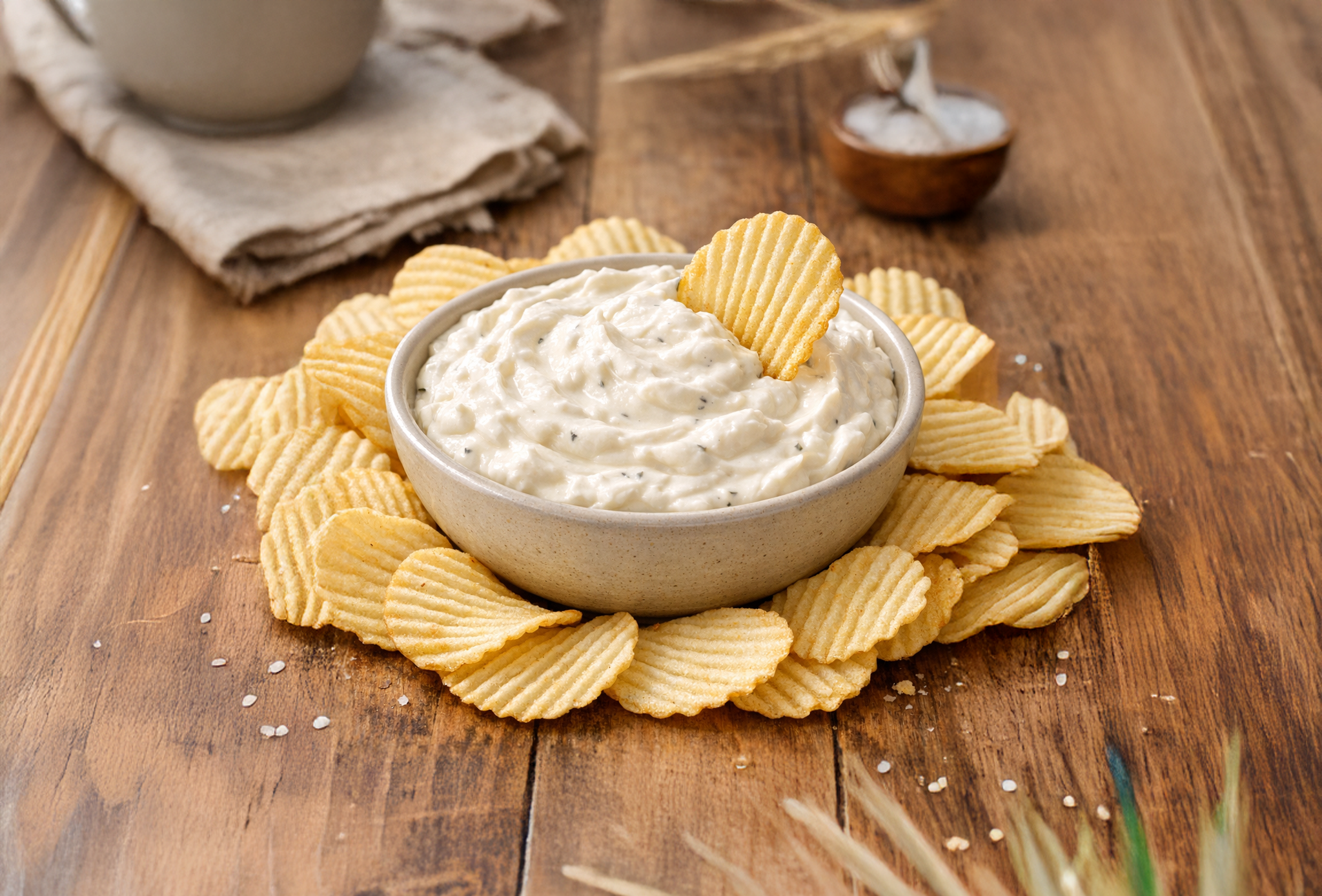 Creamy chip dip in a white bowl surrounded by crispy potato chips